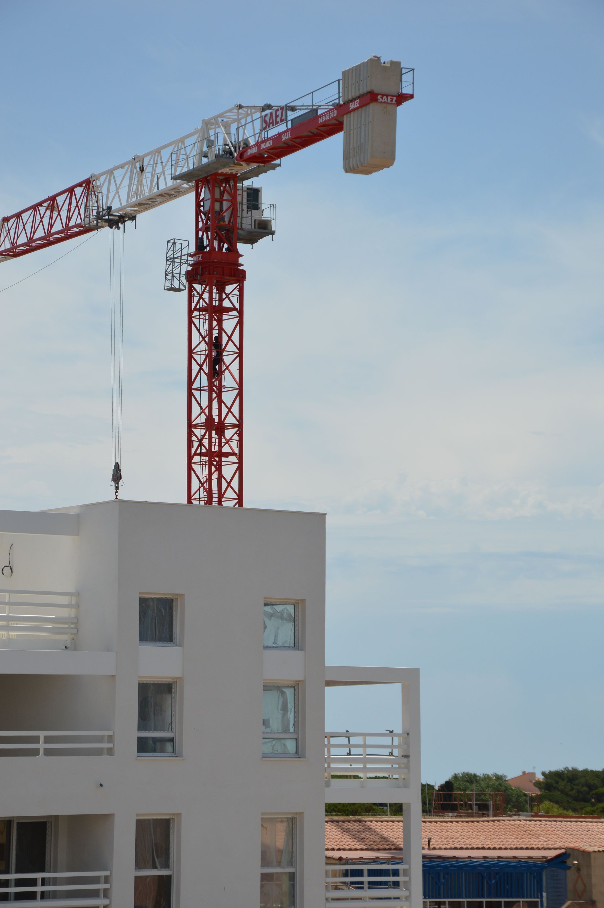Turmdrehkran über dem obersten Geschoss eines Rohbaus